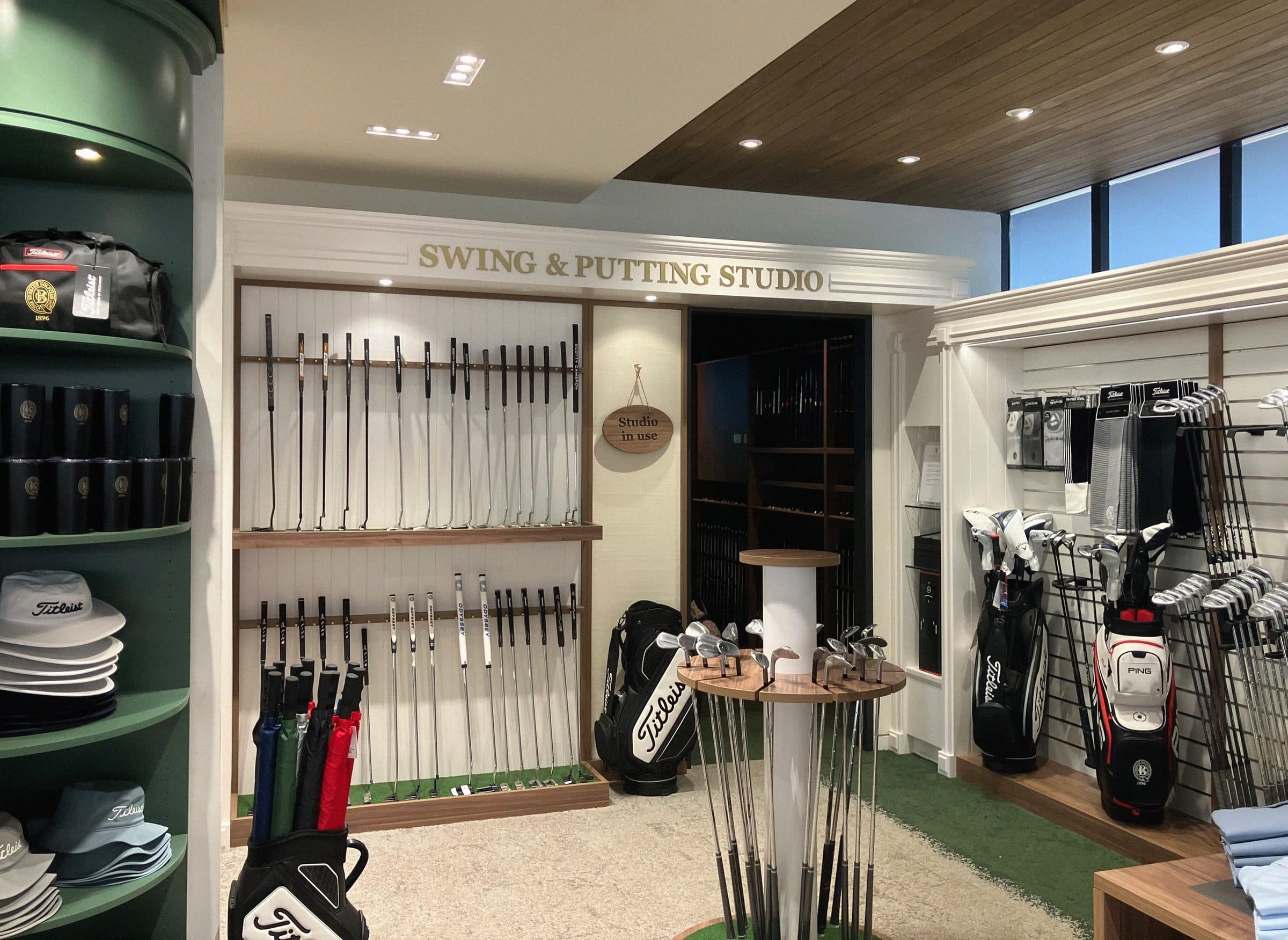 The swing and putting studio entry beside the club displays.