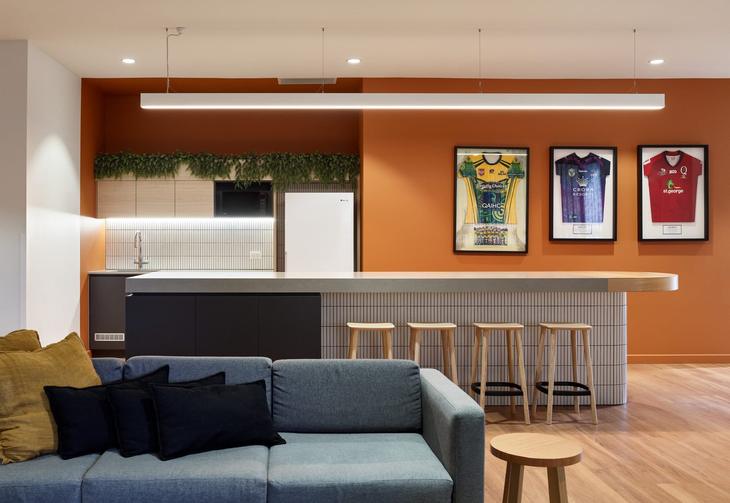 Kitchen and lounge with a tiled island bench and framed jerseys.