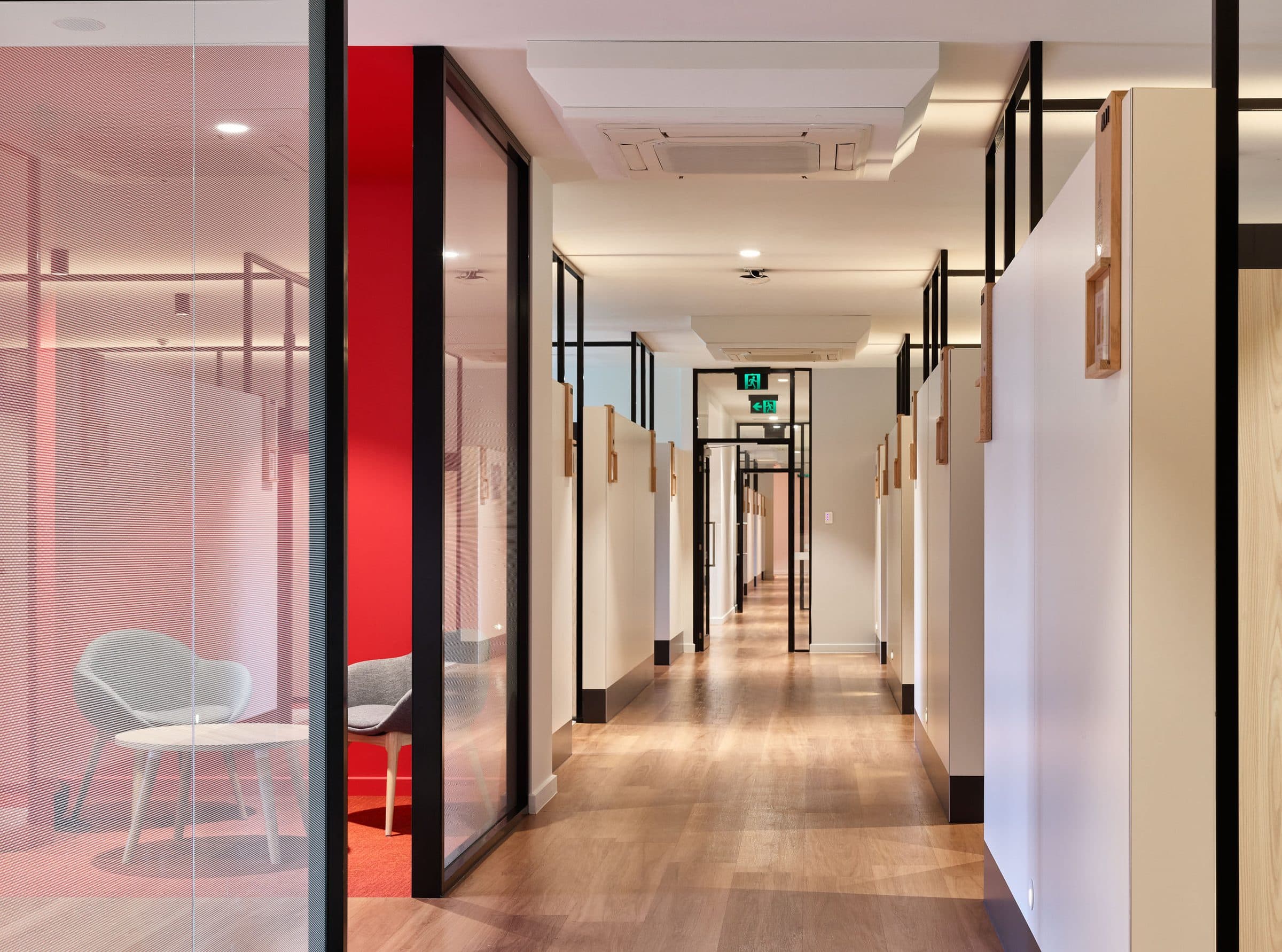 Corridor with glazed study rooms and a red-lined breakout space.