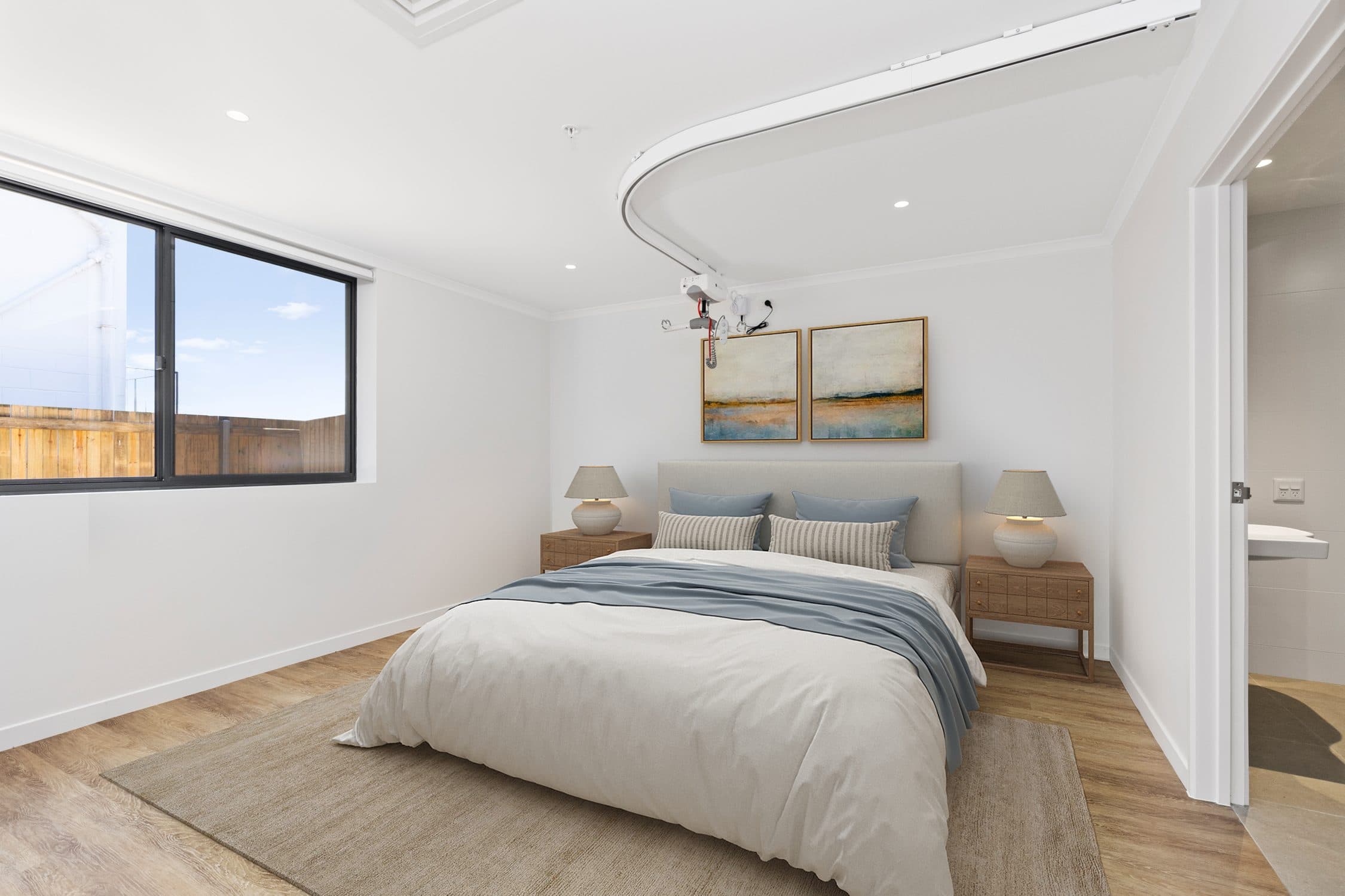 A unit bedroom with a ceiling hoist track running through to the ensuite.