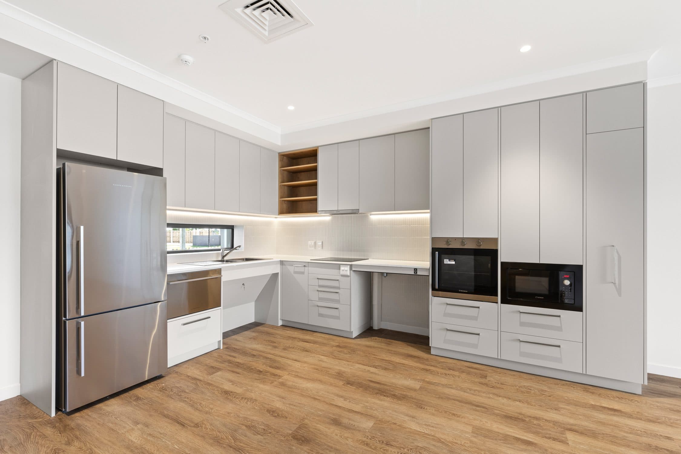 An accessible kitchen with a lowered bench, wall oven and microwave at reach height.