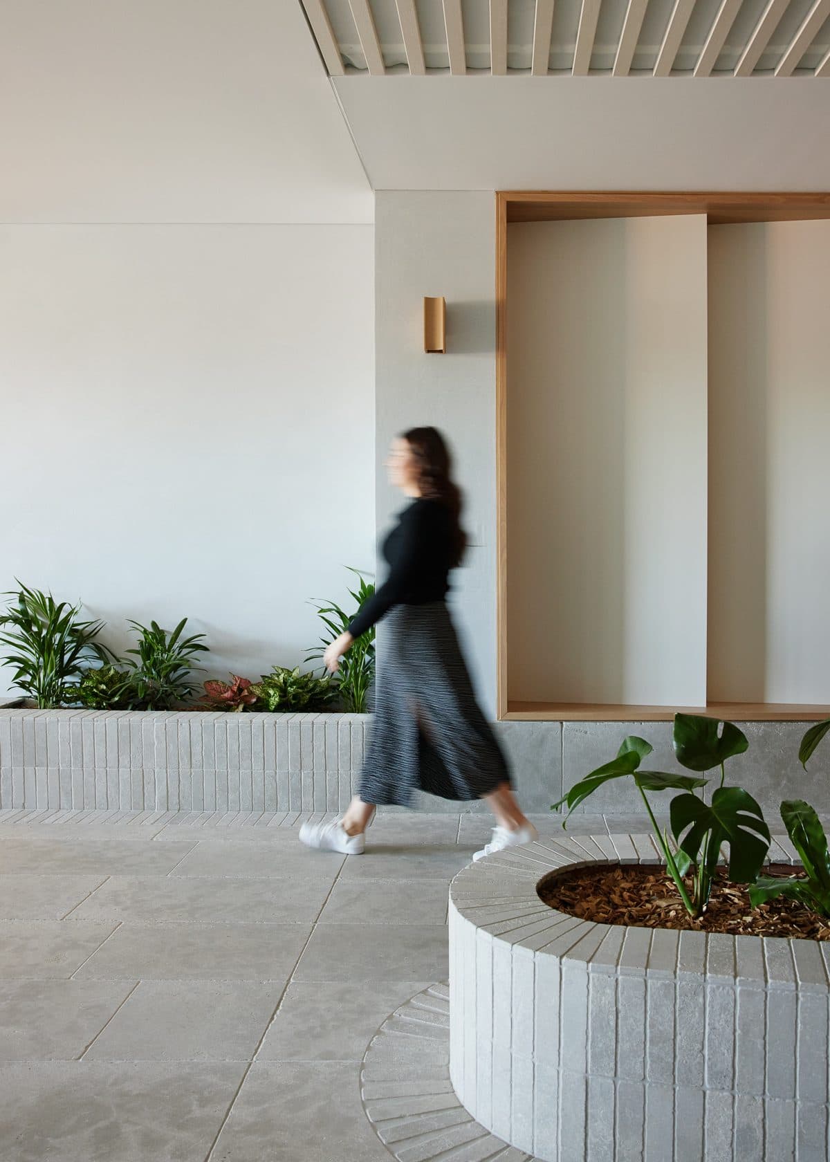 A member walking past the planters and lit wall niches in the breezeway.