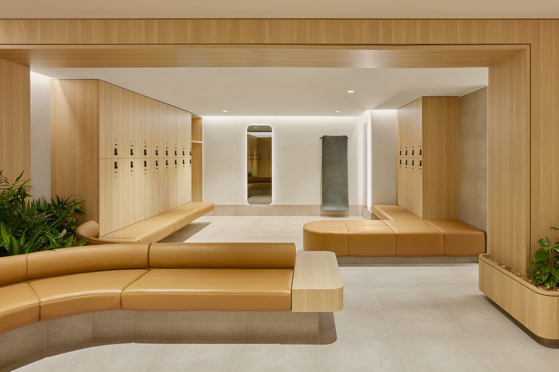 Member change room with curved upholstered seating and timber lockers.