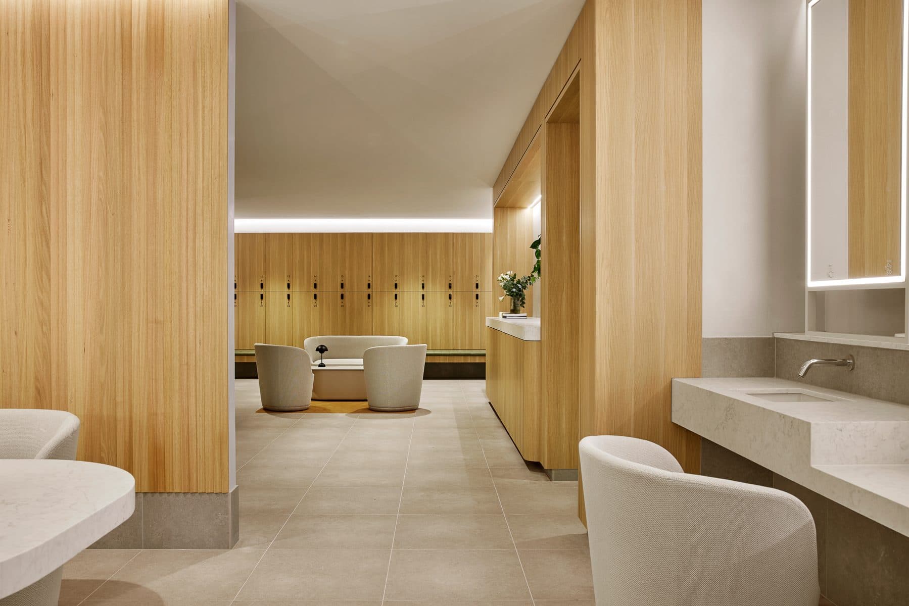 Vanity area with backlit mirrors and timber-lined walls.