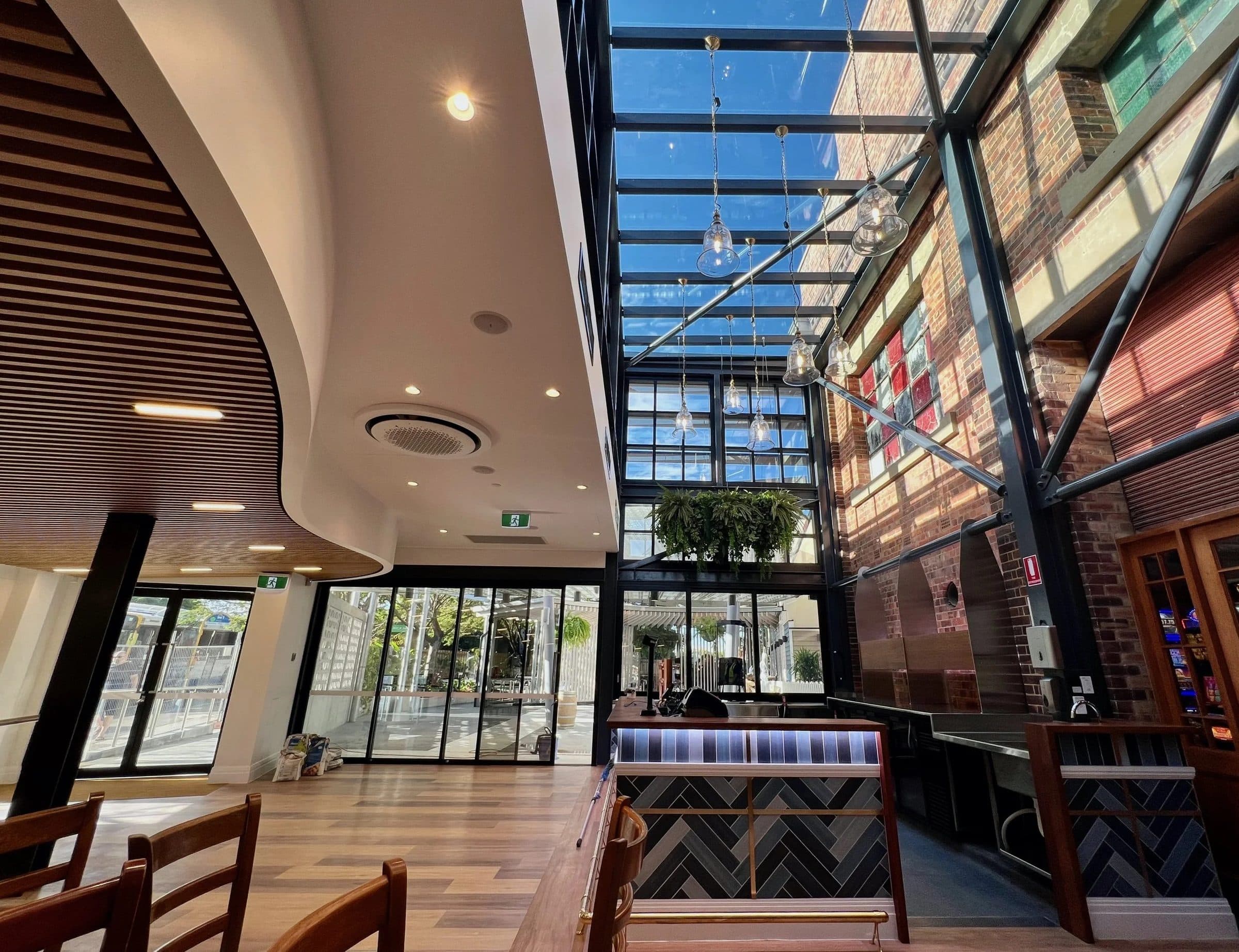 The atrium with its steel and glass roof against the substation's brick wall.