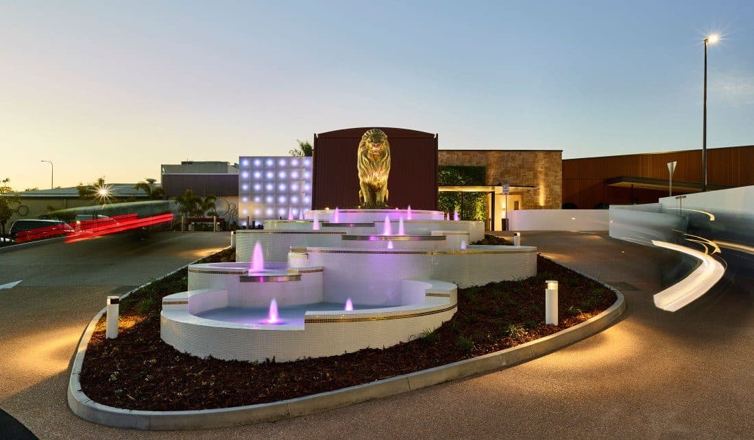 The entry forecourt and fountain lit at night.