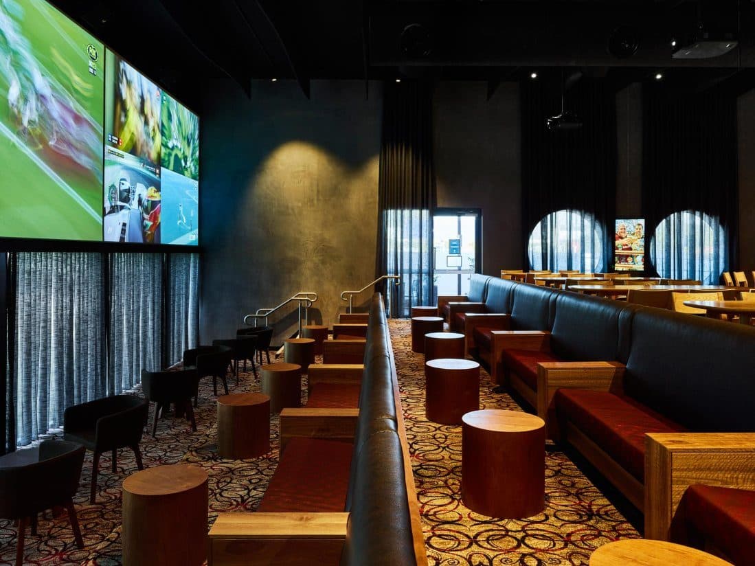 The sports lounge with booth seating and a large screen wall.