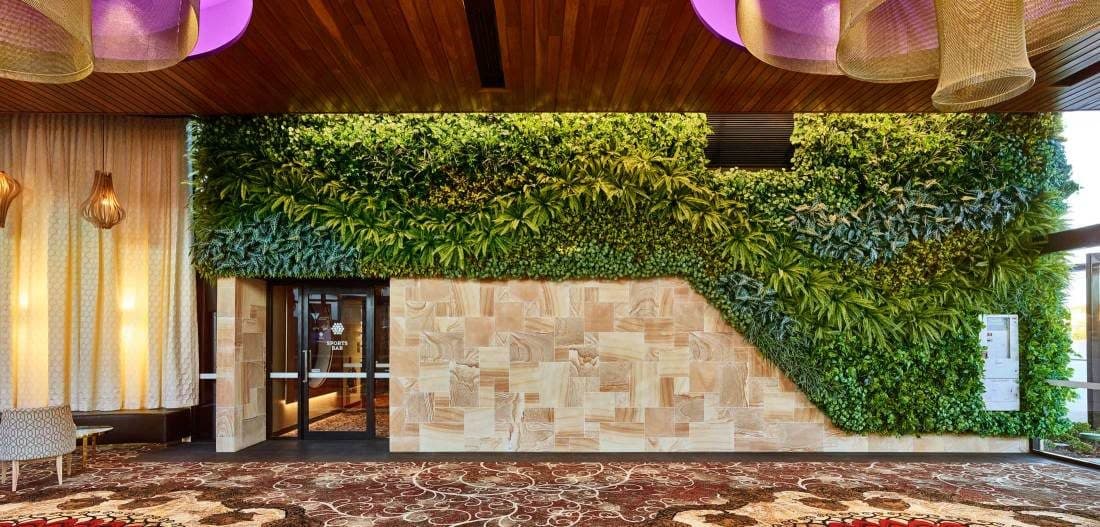 A planted green wall beside the entry doors.