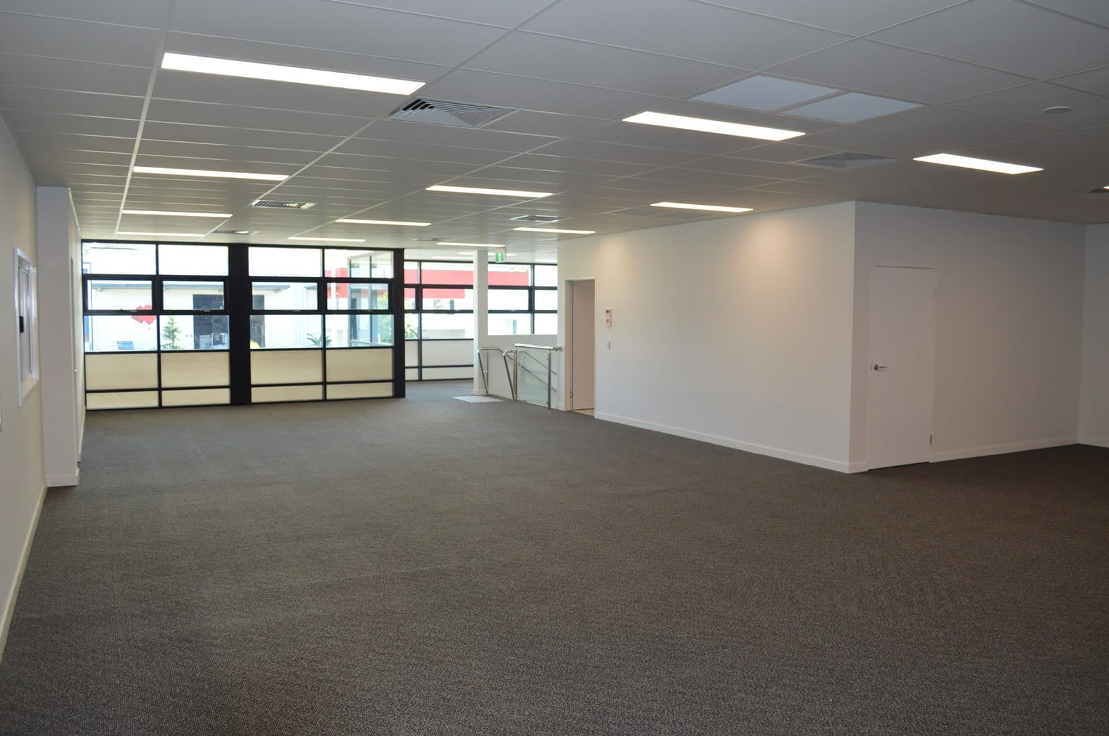 An open-plan mezzanine office with full-height glazing to the front of the building.