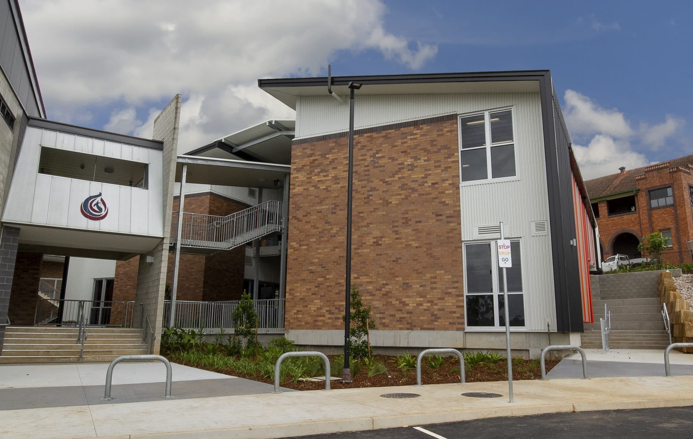 The building entry, with brickwork, white cladding and stairs up from the carpark.