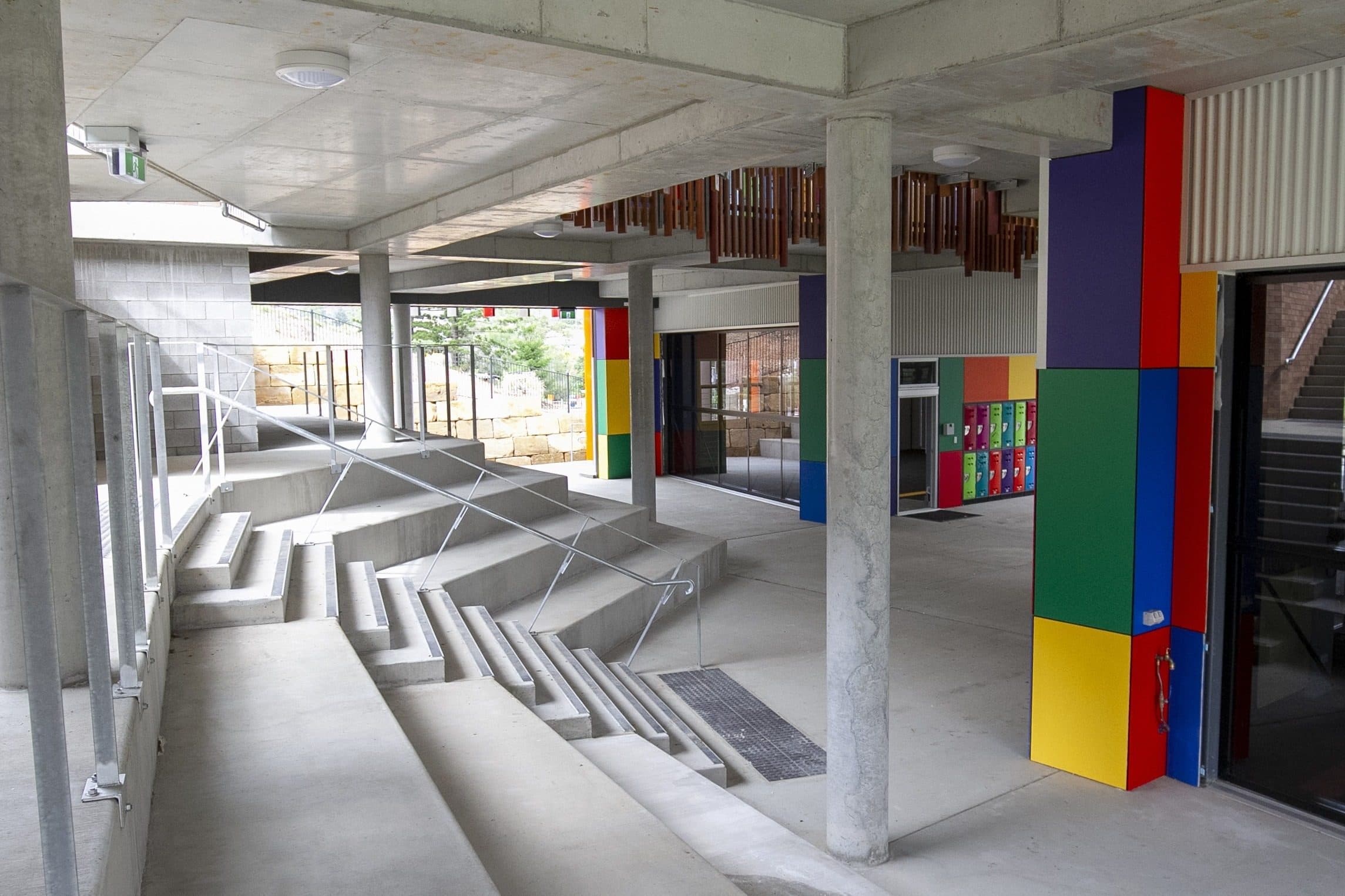 Covered stair seating under the building, with coloured panels and lockers.