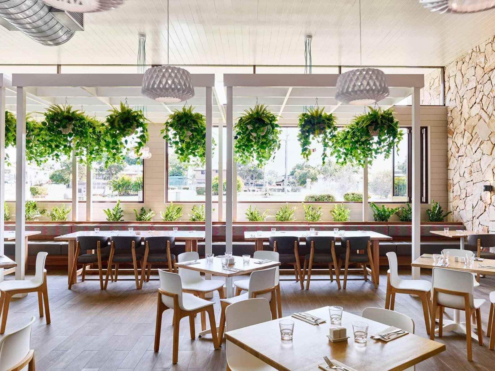 The bistro with hanging planters under a white pergola frame.