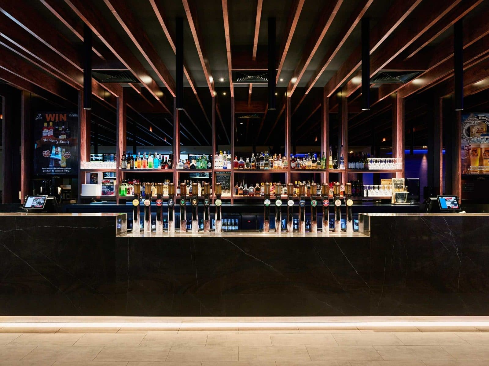 The main bar with a black stone front and timber ceiling battens.