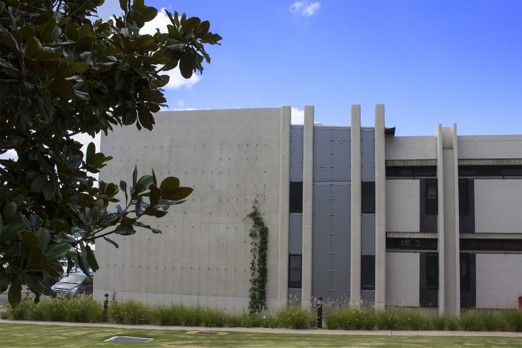 The village's concrete outer wall with vertical fins and climbing planting.
