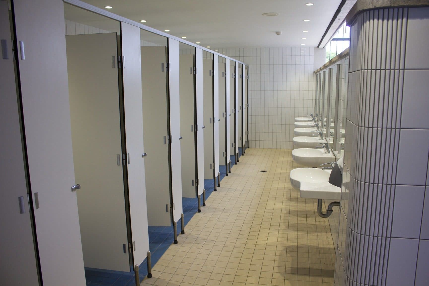 The amenities block with cubicles along one wall and basins along the other.