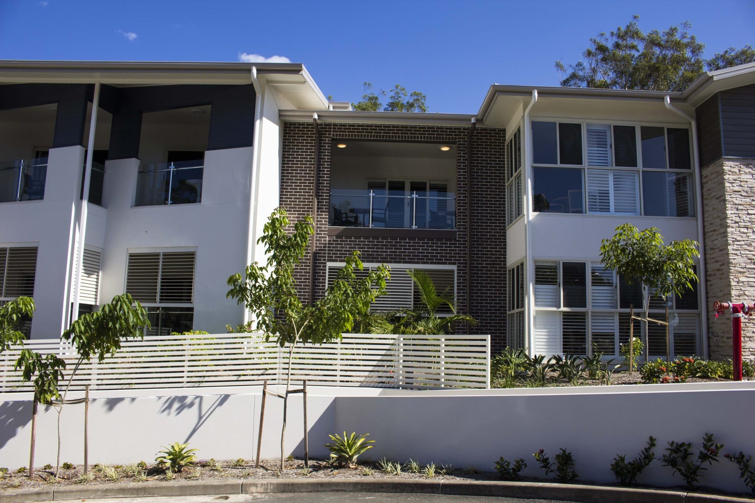 The building's brick, stone and white cladding, with balconies to the upper rooms.