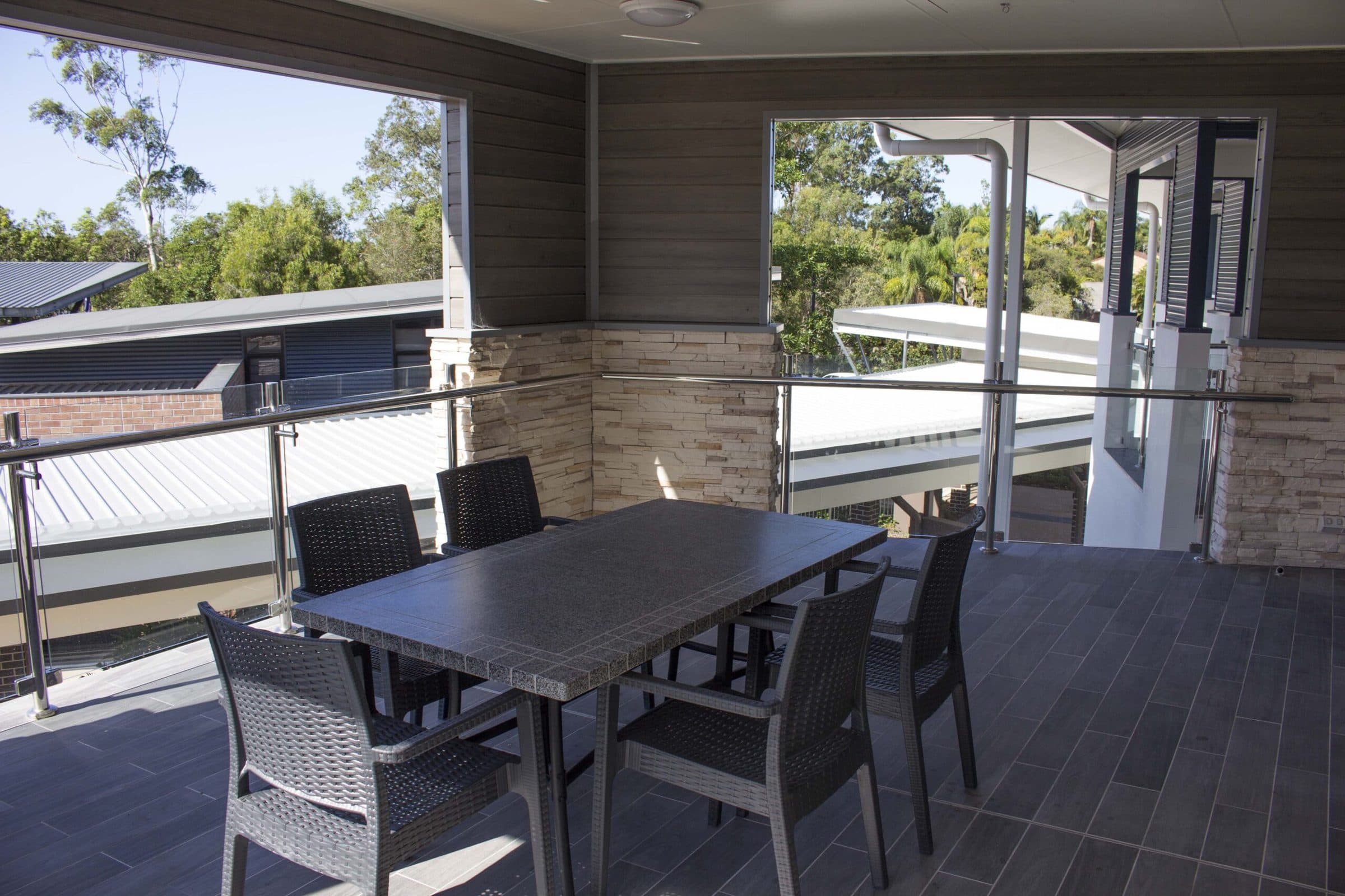 A covered balcony with an outdoor dining setting looking into the trees.
