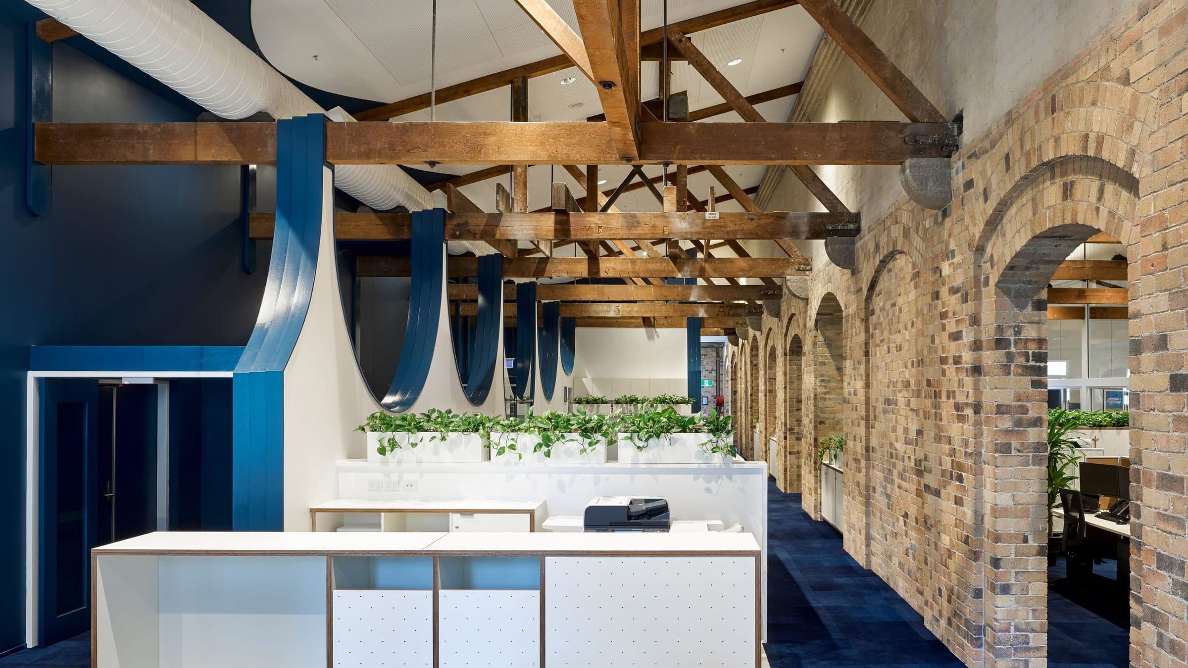 Blue semi-circular walls hung between the heritage beams and brick arches.