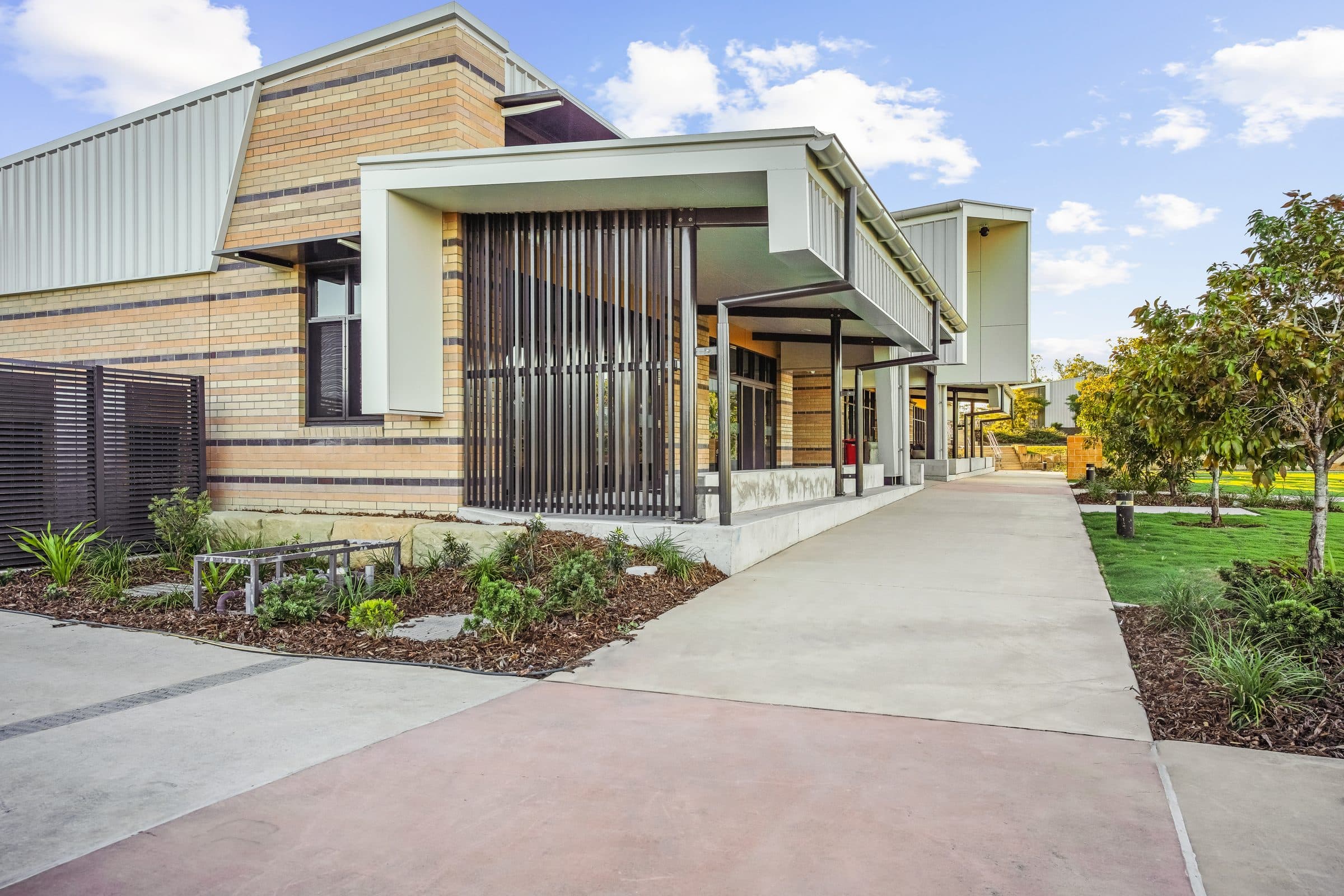A new learning block in face brick and pale cladding, with a deep entry canopy over the path.