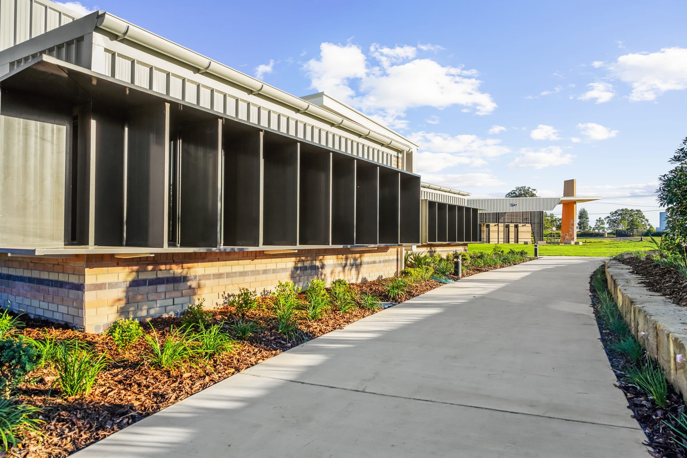 A block elevation with vertical sun screens and a landscaped path along its length.
